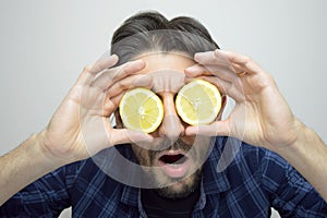 A curious young man covering his eyes with lemons discovering a new thing / new product