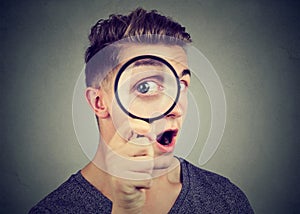 Curious young man looking through a magnifying glass