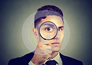 Curious young man looking through a magnifying glass