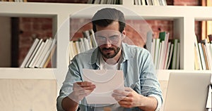 Curious young man opening envelope with business correspondence.