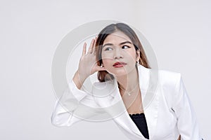 A curious young woman eavesdropping with palms open next to her ear. Isolated on a white background