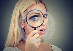 Curious young woman looking through a magnifying glass