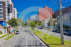 CURITIBA ,BRAZIL - MAY 12, 2016: long empty street with some autos parked at the sides and some trees on the sidewalk