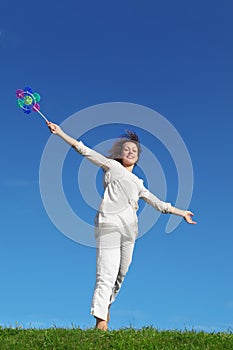 Curl woman standing on lawn, holding pinwheel toy