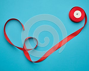 curled red satin ribbon on blue background