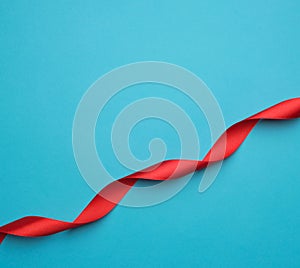 curled red satin ribbon on blue background