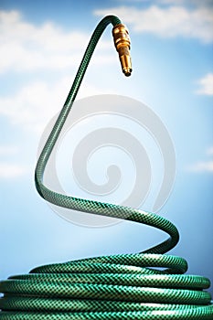 Curled up garden hose rearing up in front of blue sky