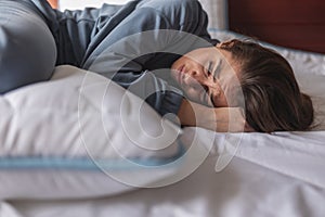 Curled up woman lying in bed having menstrual cramps