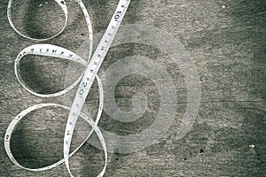 Curled white measuring tape on vintage grunge wooden background