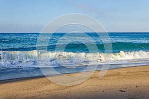 Curling breaking wave tube, foaming with backwash, with oncoming swell, on sandy shore