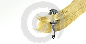 Curling brush on blonde hair with scissors on white background. Accessories for haircut with copy space