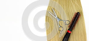 Curling brush on blonde hair with scissors on white background. Round brushing combs long blond hair closeup