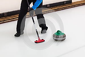 Curling - player with broom sweeping the ice before stone