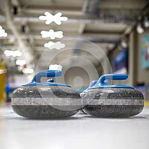 The curling stone or rock is made of granite with blue handles lie