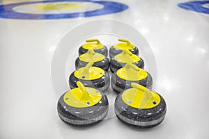 The curling stone or rock is made of granite with yellow handles lie