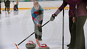 Curling training indoors - the judge measuring the distance between two stones on the ice