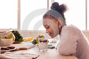 Curly African-American girl looking at sweet pudding with nuts