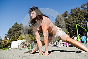 Curly and bearded man during his stretching workout on the beach