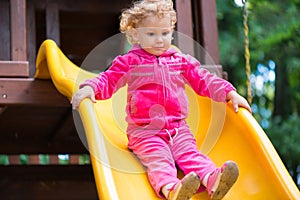 Curly blonde girl sliding at playground