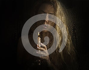 Curly blonde woman with candle on dark background