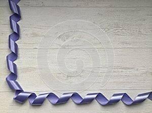 Curly blue satin ribbon in the form of spiral, flat lay with copy space on the light grey background