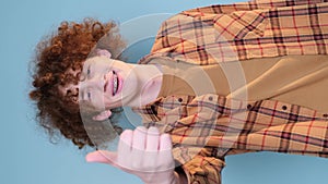 Curly boy showing thumbs up isolated on yellow background in studio. Vertical video