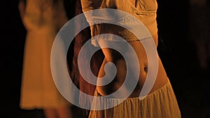 Curly brunette dancing belly dance near the fire, in the background sunset