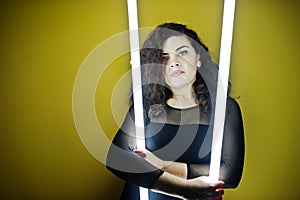 Curly brunette plus size model with two long led lamp photo