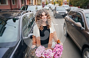 Curly brunette riding bike on street between autos.