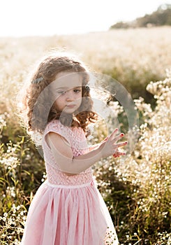 Curly cute girl baby in pink dress