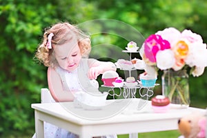 Curly cute toddler girl playing tea party with a doll