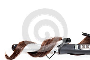 Curly dark hair with a curling iron isolated on white background