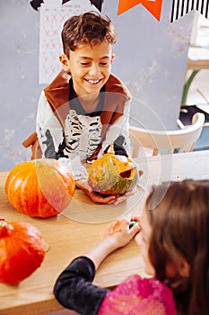 Curly dark-haired smiling boy wearing skeleton costume for Halloween