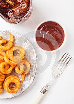 Curly fries fast food snack on wooden board with ketchup and glass of cola on stone kitchen background. Unhealthy junk food