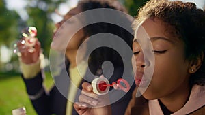 Curly girl blowing soap colorful bubbles closeup. Carefree childhood moments.