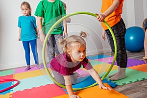 Curly girl crawling on colorful floor through hula hoops