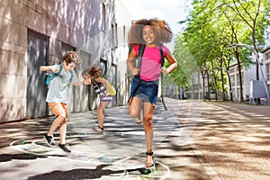 Curly girl with friends jumping hopscotch