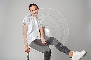 Curly girl model posing on a chair against gray background