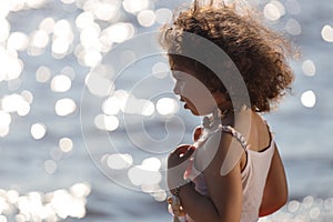 Curly girl pink dress with shell decorations on the beach