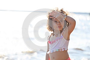 Curly girl pink dress with shell decorations on the beach