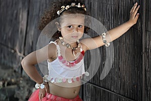 Curly girl pink dress with shell decorations on the beach