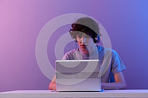 curly guy sitting at the table gaming laptop  background