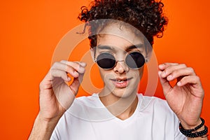 curly guy wearing sunglasses fashion youth style orange background