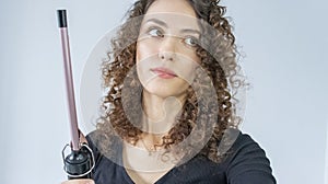 Curly Hair. Beautiful brooding woman looking up with curly hair, curling her hair, using curling tongs to get fine curls