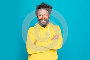 Curly hair enthusiastic man crossing arms and smiling