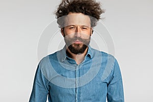 Curly hair guy in denim shirt making suspicious faces and posing