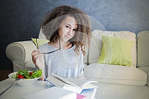 Curly hair teen girl reading book and eating salad