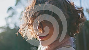 Curly-hair woman enjoy sunlight in forest portraying tranquil solitude closeup