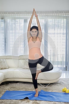 Curly hair woman exercising yoga with tree pose