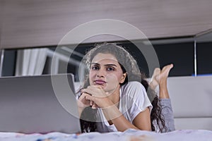 Curly hair woman lying with a laptop on the bed